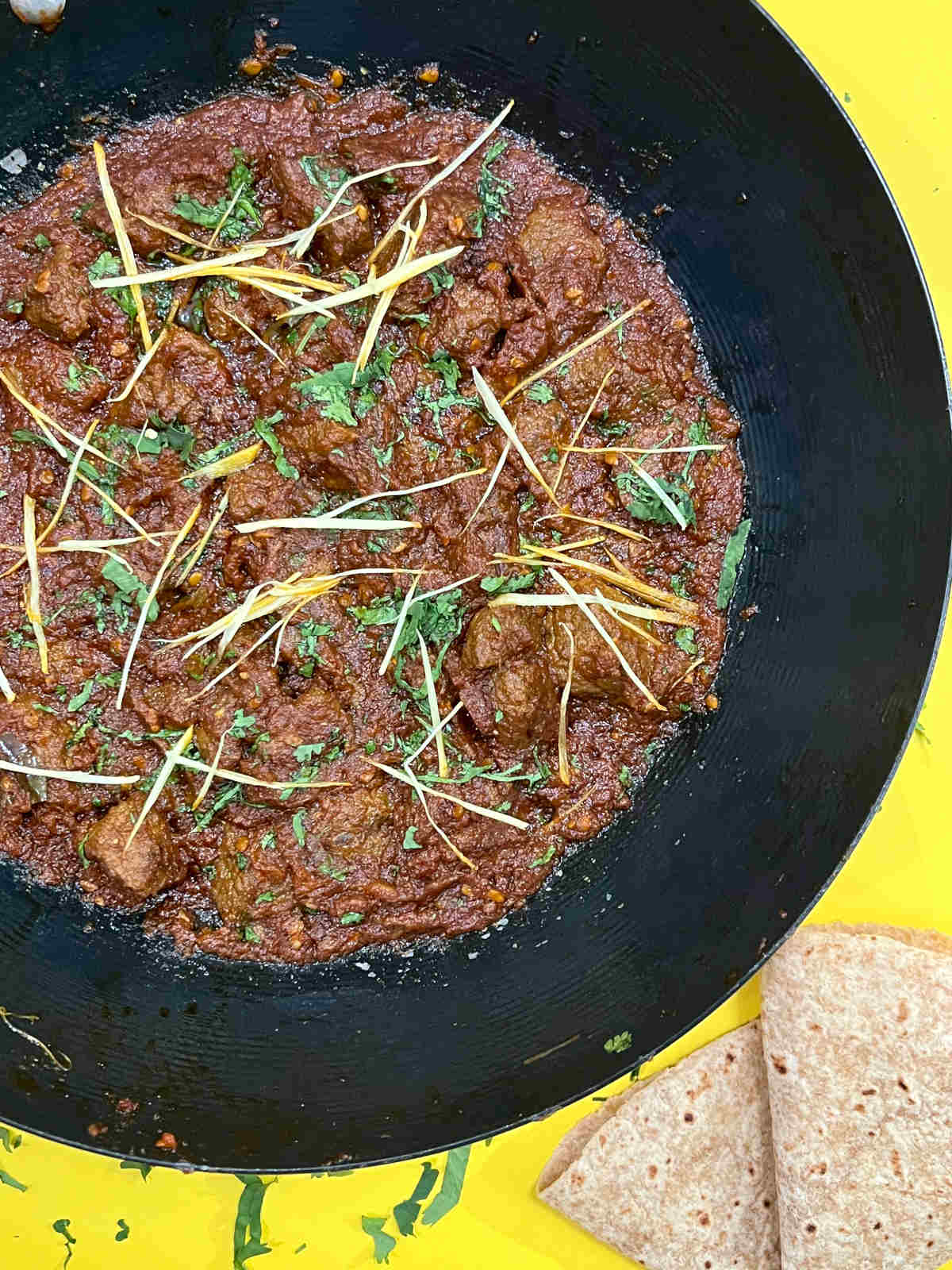beef karahi in a pan with roti on the side